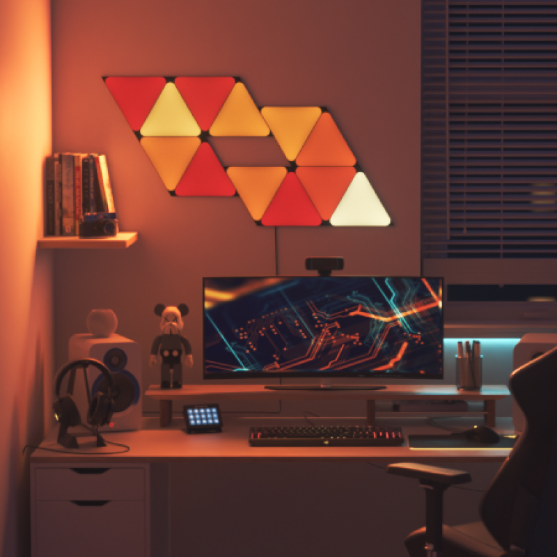 Nanoleaf Shapes Thread enabled color changing black triangle smart modular light panels mounted to a wall above a battlestation. Similar to Philips Hue, Lifx. HomeKit, Google Assistant, Amazon Alexa, IFTTT.